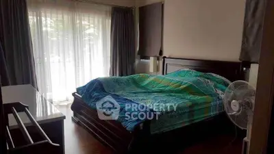 Spacious bedroom with large windows and elegant wooden furniture, perfect for a cozy retreat.