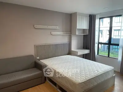 Modern bedroom with large window, cozy sofa, and stylish shelving in a bright apartment.