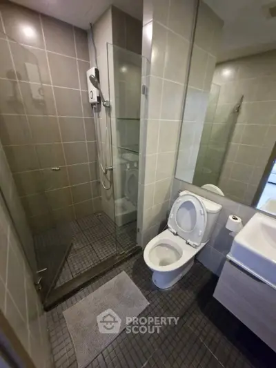 Modern bathroom with glass shower and sleek fixtures in contemporary apartment.