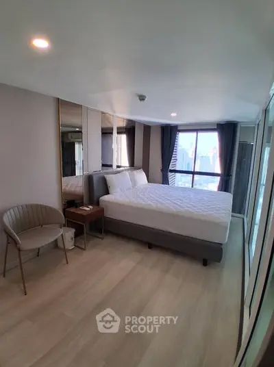 Spacious modern bedroom with city view, featuring elegant decor and ample natural light.
