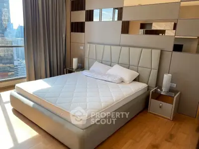 Luxurious bedroom with city view, modern decor, and elegant furnishings in high-rise apartment.
