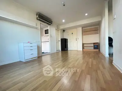 Spacious unfurnished living room with wooden flooring and built-in shelves, ideal for customization.