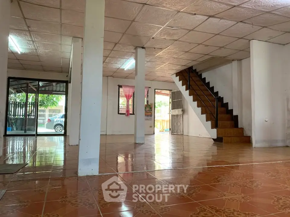 Spacious open-plan living area with tiled flooring and staircase in a bright home interior.