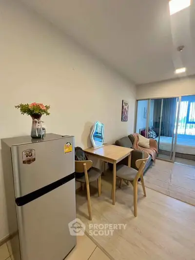 Modern apartment interior with dining area and cozy living space, featuring a sleek refrigerator and stylish decor.