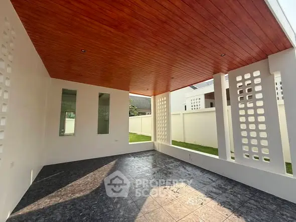 Spacious modern patio with wooden ceiling and stylish tile flooring, perfect for outdoor relaxation.