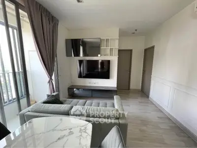 Modern living room with sleek furniture and large TV, featuring floor-to-ceiling windows and elegant decor.