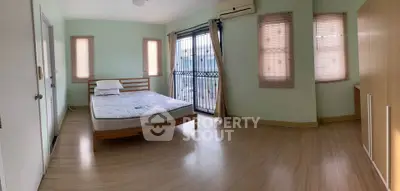 Spacious bedroom with natural light, wooden flooring, and balcony access in modern apartment.