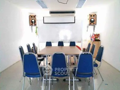Spacious meeting room with modern chairs and audio setup, ideal for business gatherings.