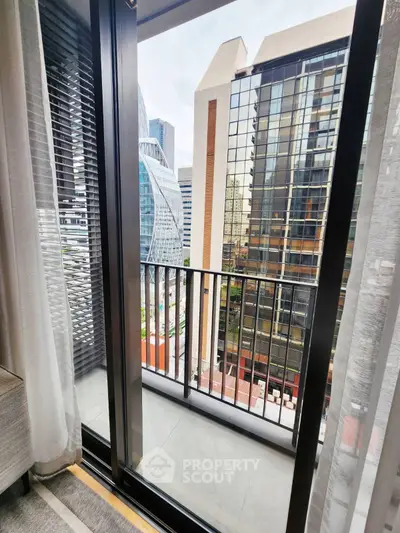 Modern city view from a stylish apartment balcony with glass railing.