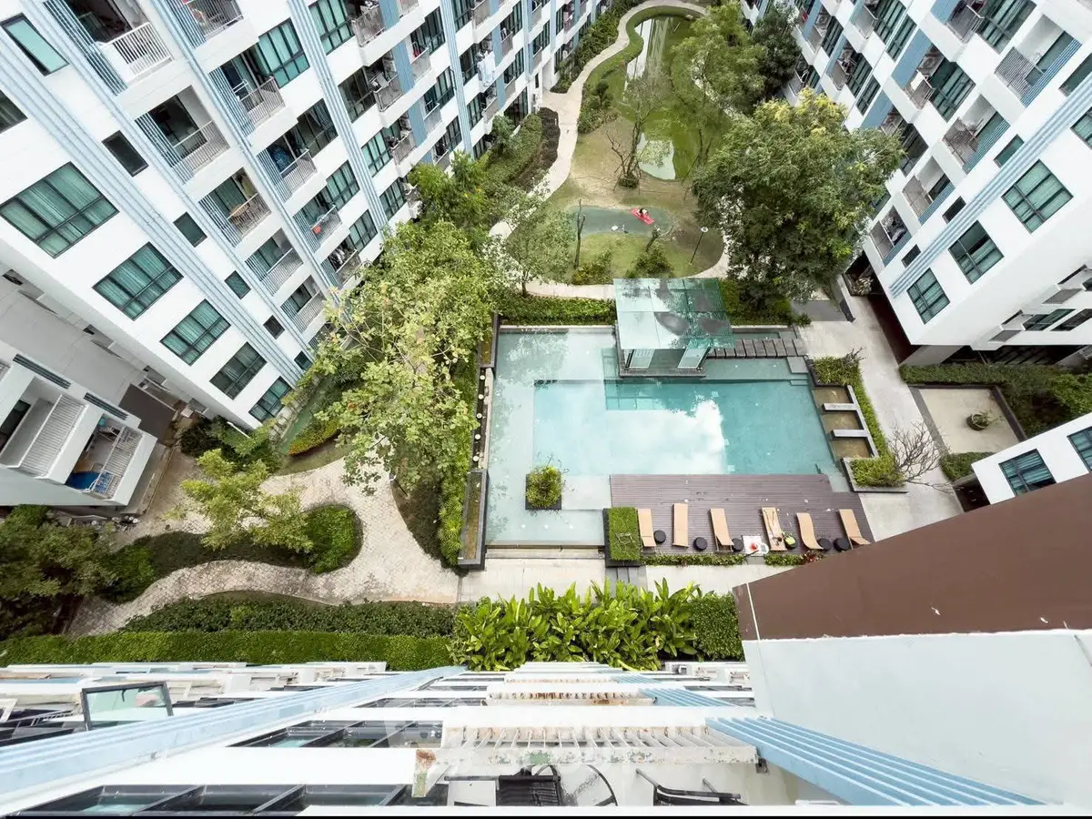 Stunning aerial view of modern apartment complex with lush garden and inviting pool area.