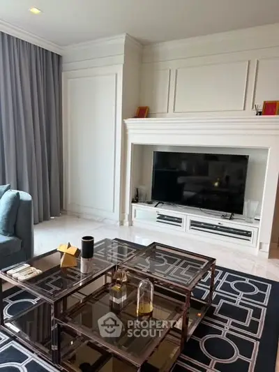 Elegant living room with modern decor, featuring a stylish glass coffee table and a large flat-screen TV.