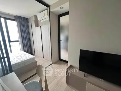 Modern bedroom with sleek furniture and natural light, featuring a large window and air conditioning unit.