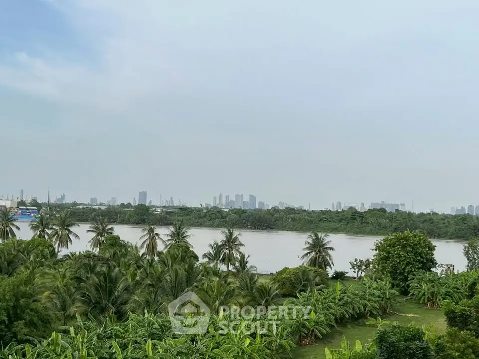 Scenic river view with lush greenery and distant city skyline, perfect for tranquil living.