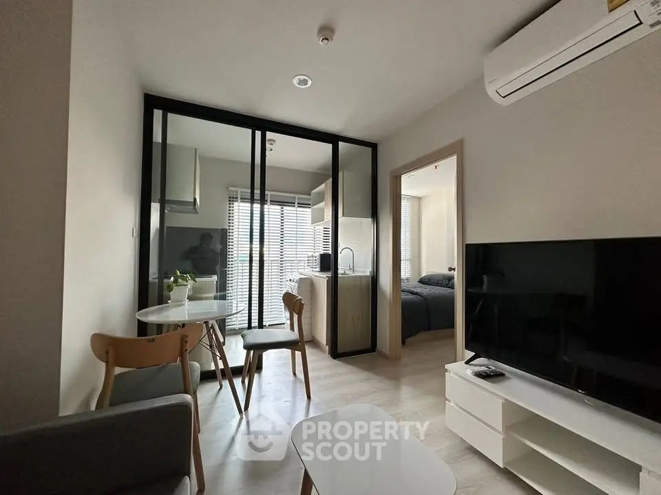 Modern apartment interior with open layout, featuring a cozy living area, dining space, and a glimpse of the bedroom.