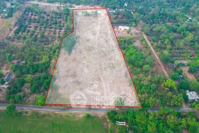 Expansive aerial view of a vast plot of land outlined in red, surrounded by lush greenery and trees.