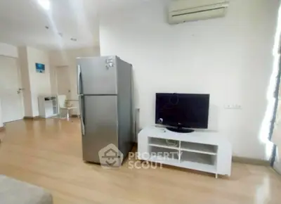 Modern living room with fridge and TV, featuring wooden flooring and air conditioning.
