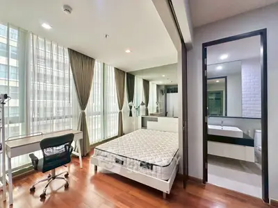 Spacious modern bedroom with large windows and ensuite bathroom in a high-rise apartment.