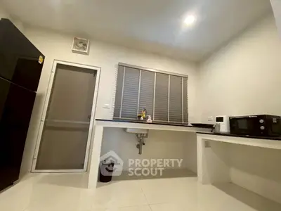 Modern kitchen with sleek design, featuring a black refrigerator and microwave, ideal for urban living.