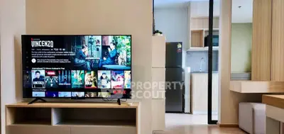 Modern living room with sleek TV and stylish kitchen in open layout apartment.