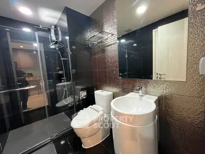 Modern bathroom with sleek black tiles and glass shower enclosure