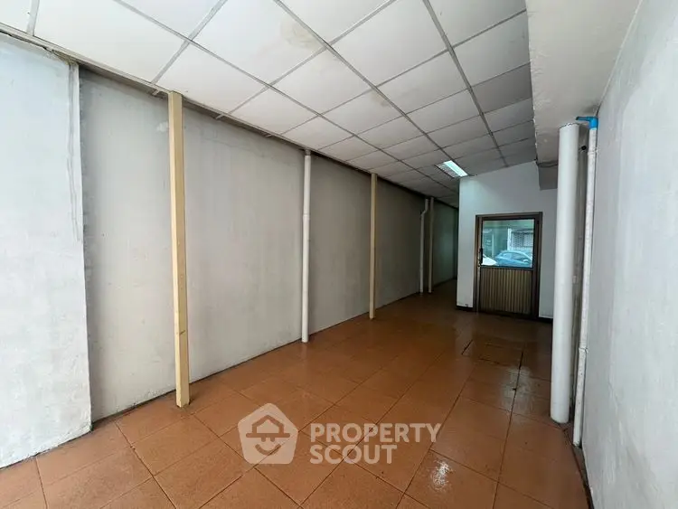 Spacious commercial space with tiled flooring and ceiling panels, ideal for business setup.