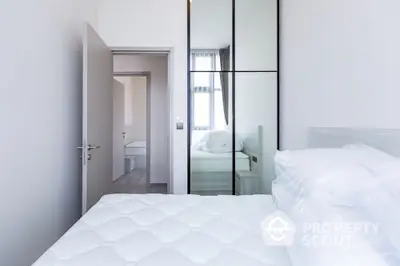 Modern minimalist bedroom with mirrored wardrobe and plush bedding