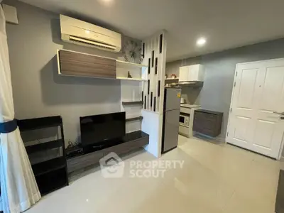 Modern living room with sleek furniture and integrated kitchen area, featuring air conditioning and stylish shelving.