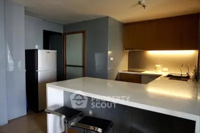 Modern kitchen with sleek design, featuring a breakfast bar and stainless steel appliances.