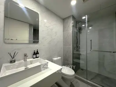 Modern bathroom with sleek design, featuring a glass shower and elegant fixtures.