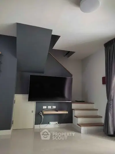 Modern living room with sleek TV setup and stylish staircase