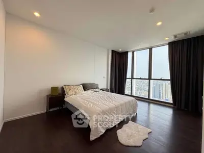 Spacious bedroom with large windows offering stunning city views, featuring elegant hardwood floors and modern decor.