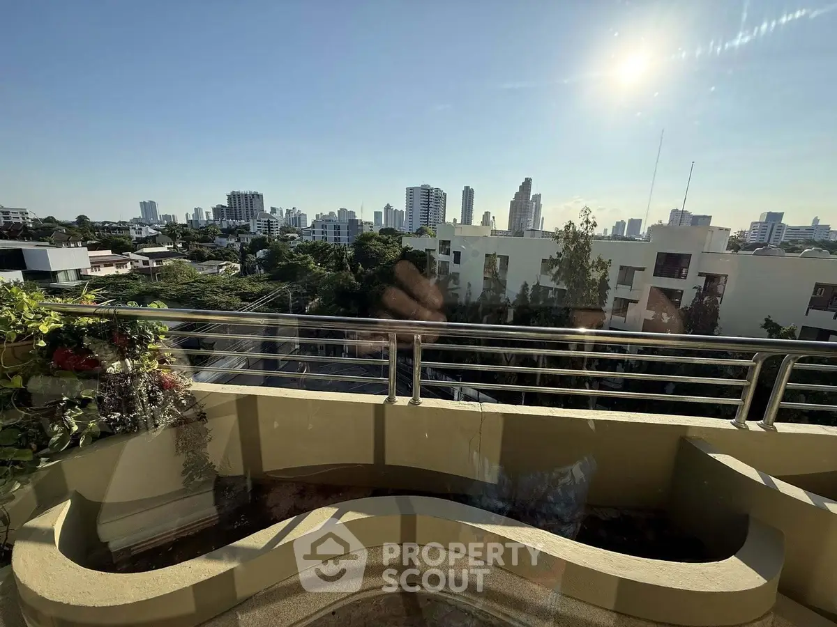 Stunning cityscape view from a spacious balcony with modern railing and lush greenery.