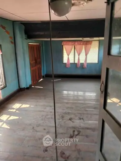 Spacious empty room with wooden floors and large windows, ideal for customization.