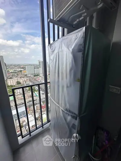High-rise balcony with city view and covered refrigerator, perfect for urban living.
