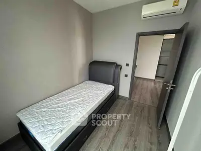 Cozy single bedroom with modern flooring and air conditioning in a stylish apartment.
