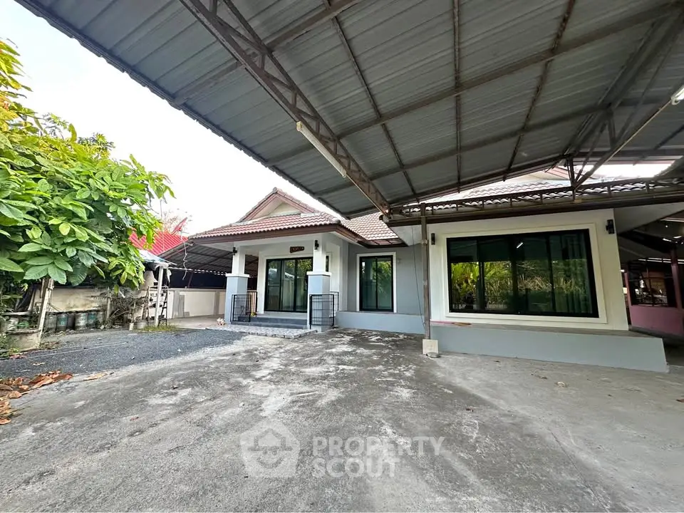 Spacious single-story home with large carport and lush greenery, perfect for family living.
