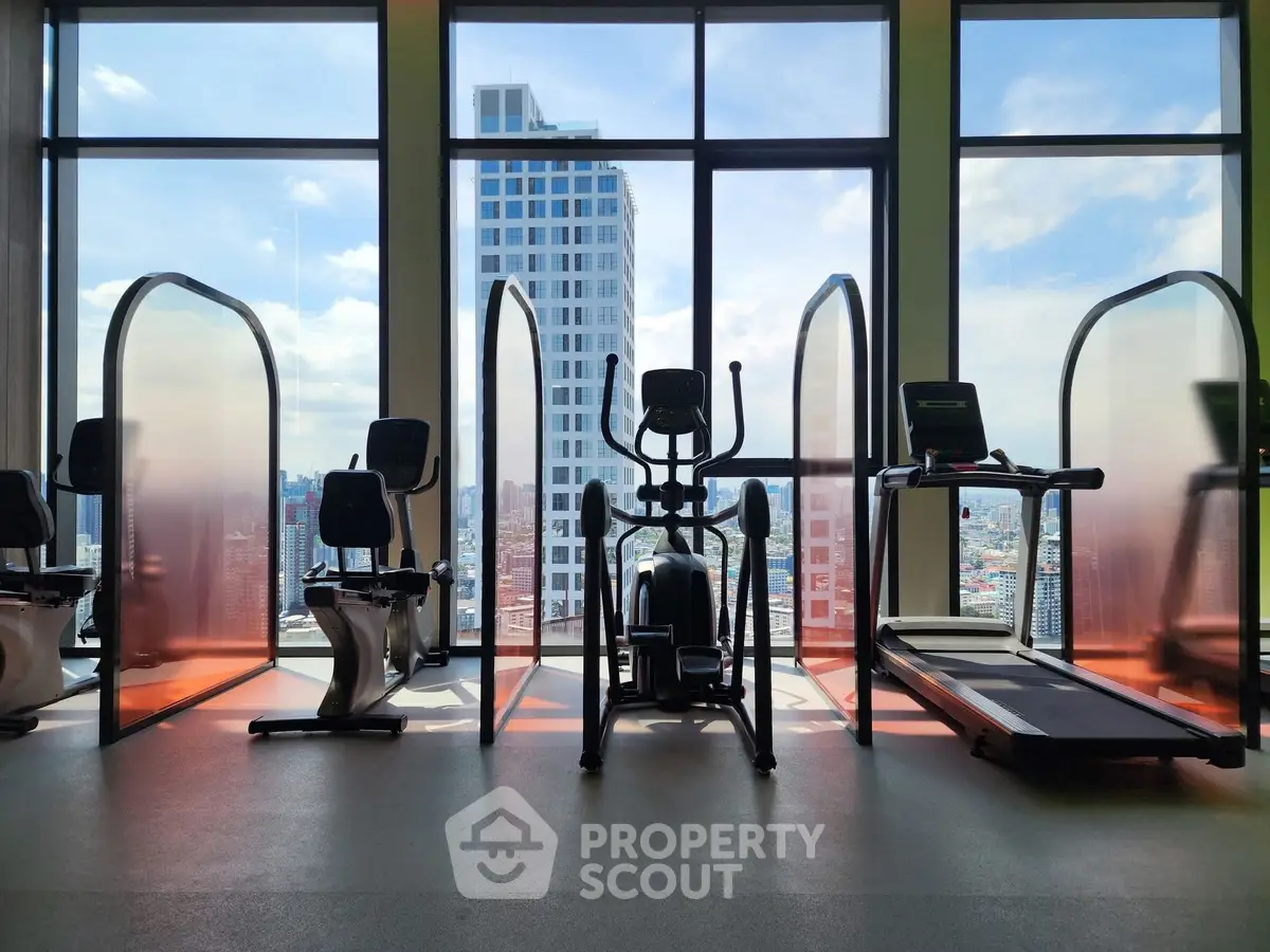 Modern gym with city view and exercise equipment in high-rise building.