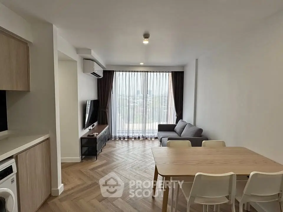Modern living room with sleek furniture and large window, featuring a cozy atmosphere.