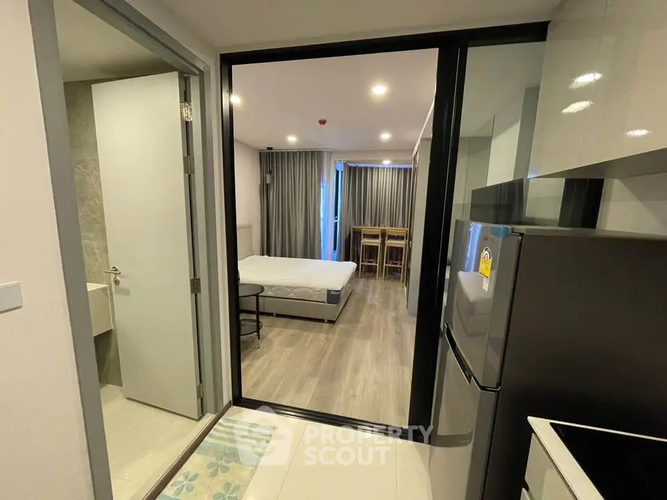 Modern studio apartment with sleek kitchen and cozy bedroom area, perfect for urban living.