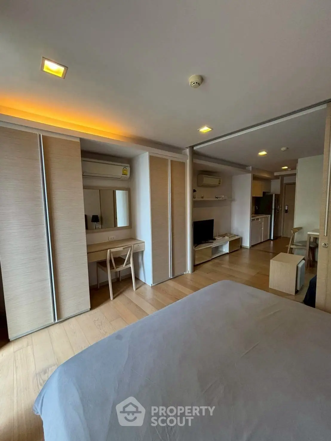 Modern bedroom with wooden flooring and built-in wardrobe, featuring a cozy workspace and sleek design.