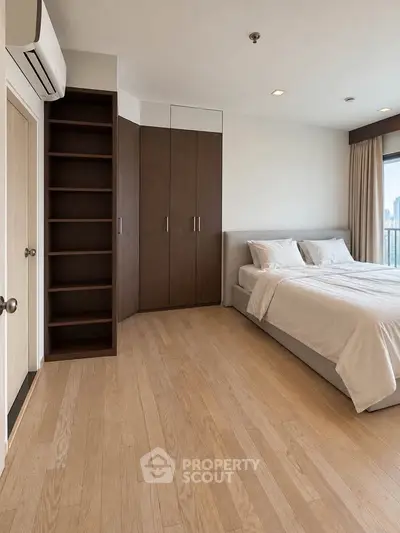 Spacious modern bedroom with wooden flooring and built-in wardrobe in a high-rise apartment.