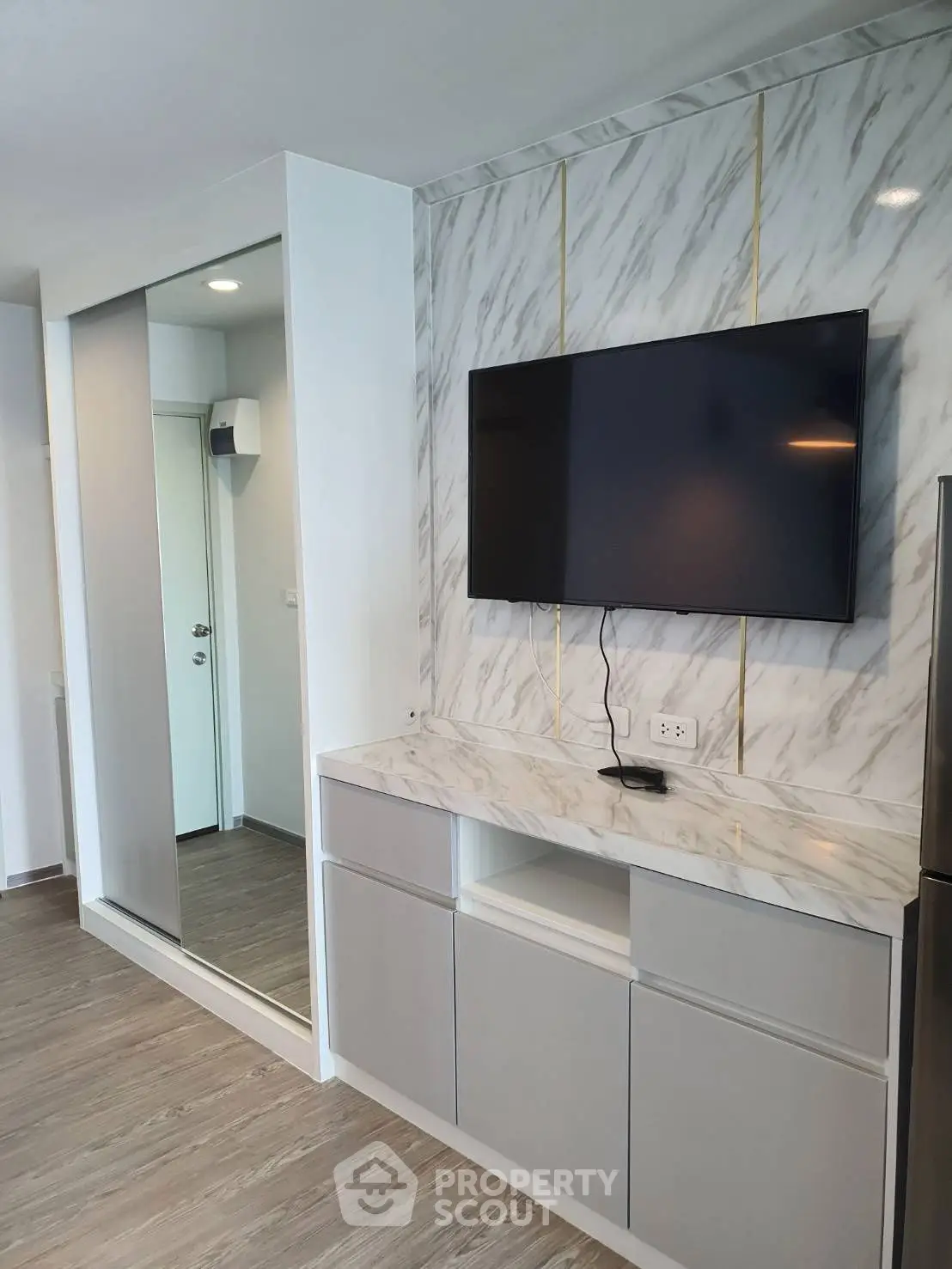 Modern living room with marble accent wall and mounted TV in stylish apartment.