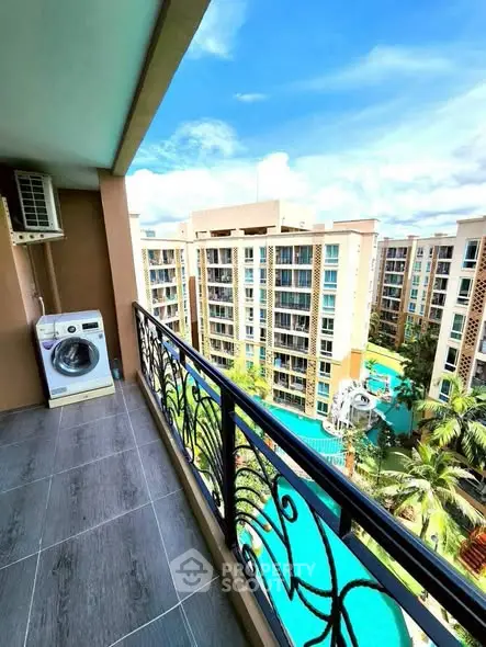 Stunning balcony view overlooking modern apartment complex with pool and lush greenery.