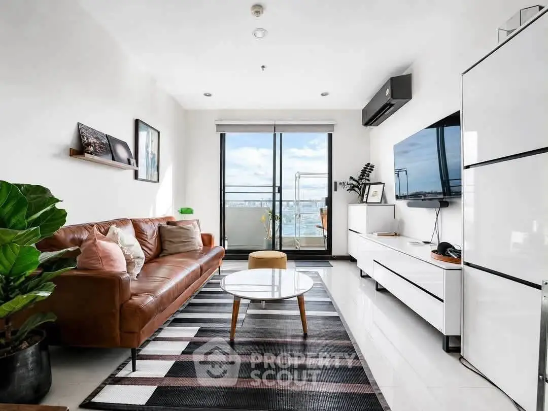 Modern living room with leather sofa, large TV, and balcony view in a stylish apartment.