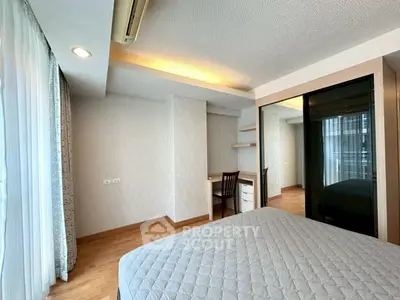 Spacious bedroom with modern decor and built-in study area, featuring large windows for natural light.