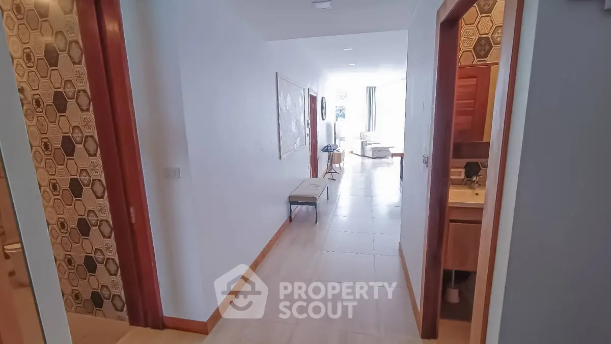 Spacious hallway leading to a bright living area with modern decor and stylish tile accents.