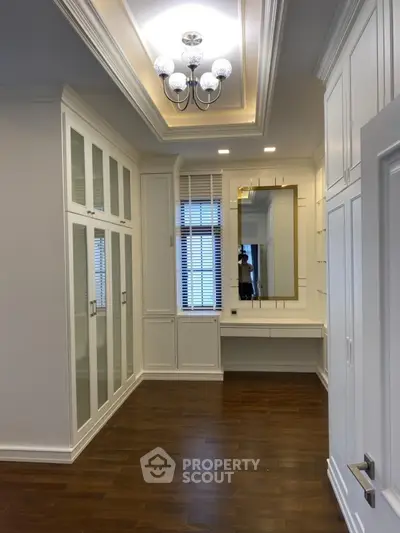 Elegant walk-in closet with hardwood floors and built-in cabinetry