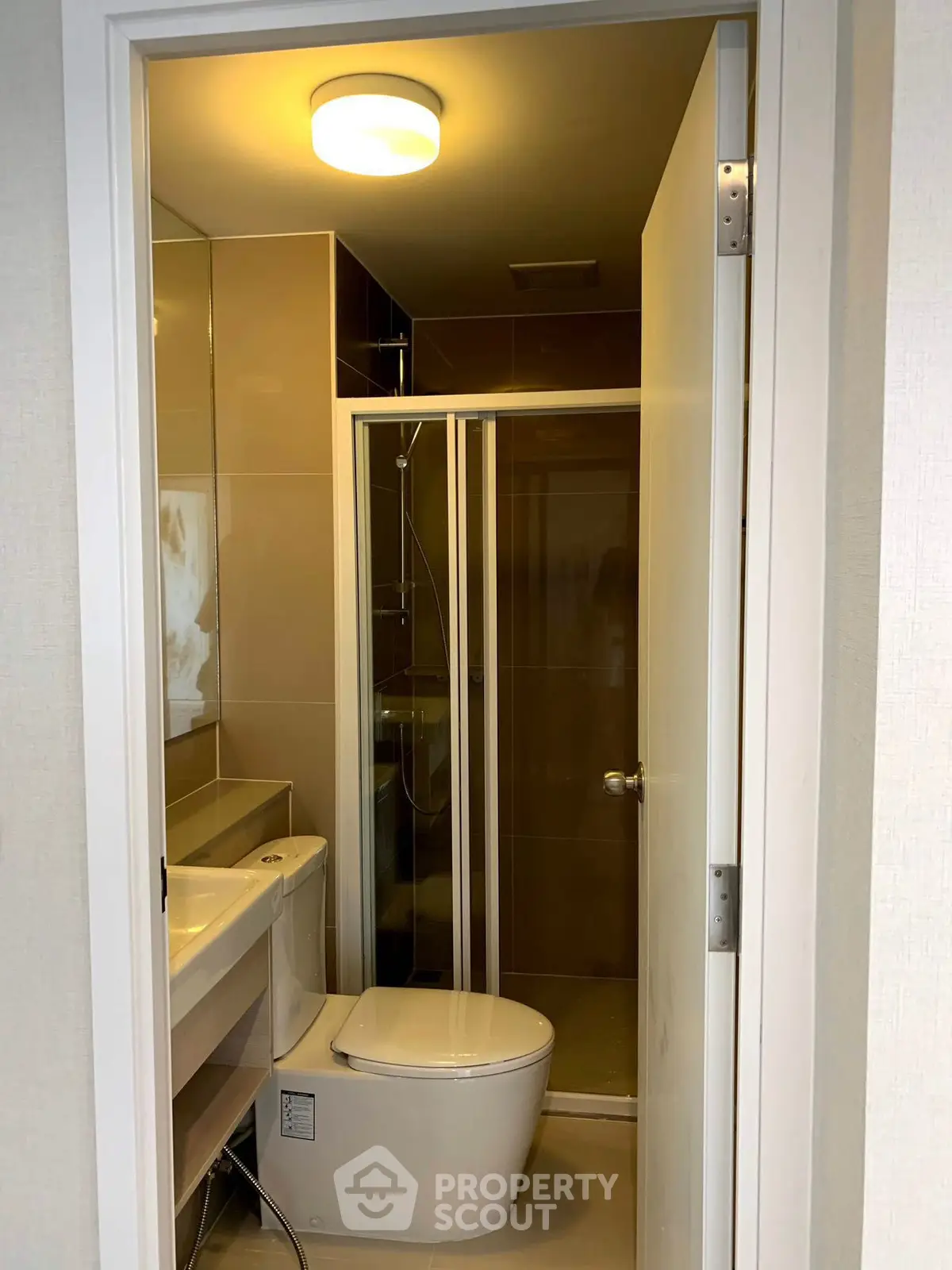 Compact modern bathroom with shower and toilet in sleek design.