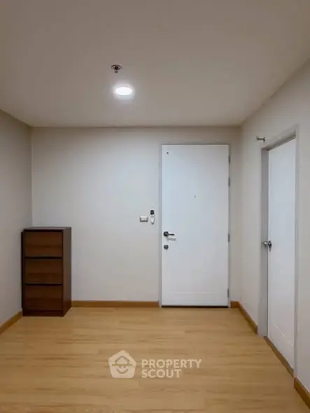 Spacious minimalist room with wooden flooring and white doors, ideal for versatile interior design.