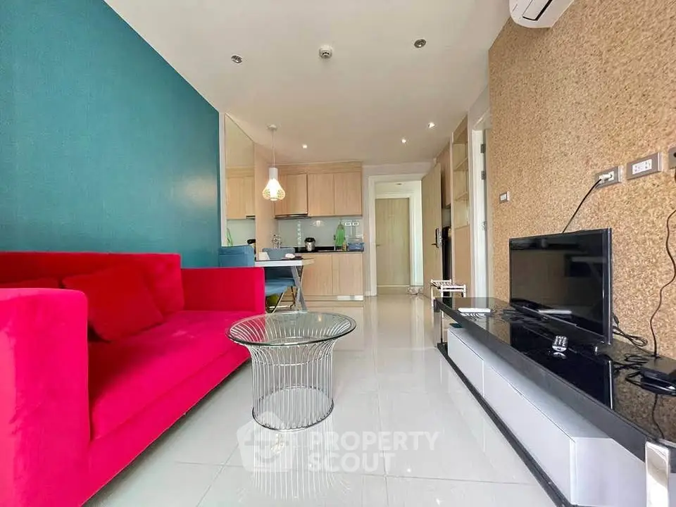 Modern living room with vibrant red sofa and sleek TV setup in stylish apartment.